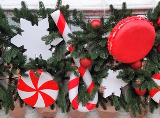 The facades of buildings and streets of the city are decorated with green Christmas tree branches, balls and garlands