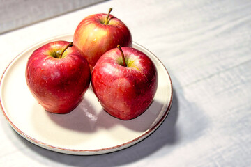 Three apples are on a white plate