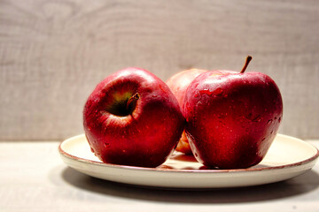 Three red apples are sitting on a white plate