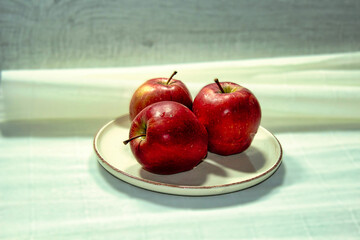 Three apples are on a white plate
