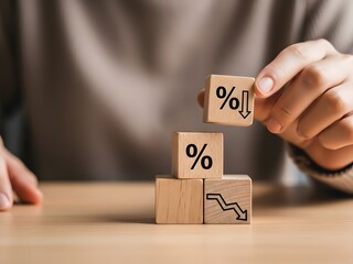 A close up view shows hands carefully assembling wooden blocks with percentage signs and declining graph icons representing financial downturns and market analysis