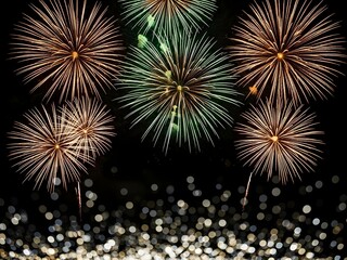 Fototapeta premium A stunning display of vibrant fireworks illuminates the night sky bursting with golden and green hues against a dark backdrop