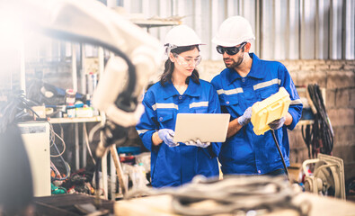 Engineers team mechanic using computer controller Robotic arm for welding steel in steel factory workshop. Industry robot programming software for automated manufacturing technology