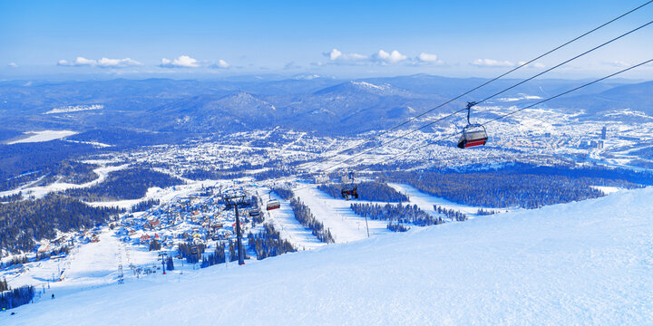 Panoramic View from mount peak Zielonaya on Sheregesh ski resort and Altai mountains, banner. Active winter rest,  ski slopes and Ski lift, clear blue sky and forest, beautiful nature, sport leisure.