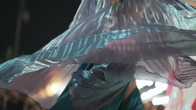 Elegant woman belly dance with costume adorned with reflective accents during a mesmerizing performance, slow motion