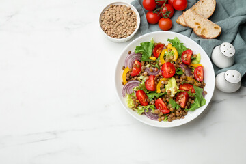 Delicious lentil salad and ingredients on white marble table, flat lay. Space for text