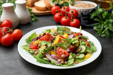 Tasty salad with lentils and vegetables on grey textured table, closeup