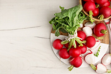 Fresh whole and cut radishes on white marble table, flat lay. Space for text