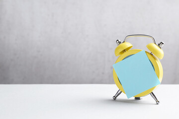 Alarm clock with sticky note on white table. Space for text
