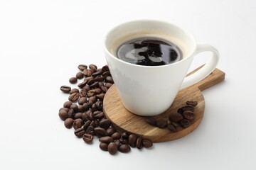 Cup of aromatic coffee and roasted beans on white background, closeup