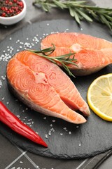 Pieces of salmon fillet with spices and lemon on table, closeup