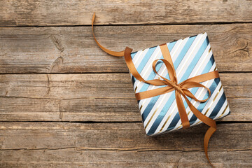 Beautifully wrapped gift on wooden table, top view. Space for text