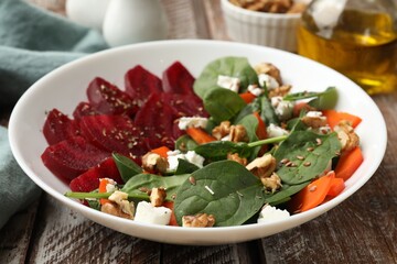 Delicious salad with beetroot, spinach, cheese, walnuts and carrot on wooden table, closeup