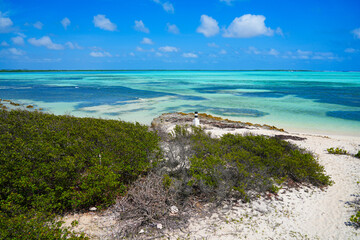 Striped navigation marker on Sorobon Beach in Lac Bay, a tropical lagoon with shallow turquoise...
