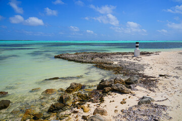 Striped navigation marker on Sorobon Beach in Lac Bay, a tropical lagoon with shallow turquoise...