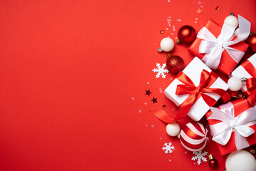 Red and white Christmas decorations and gifts on red background.