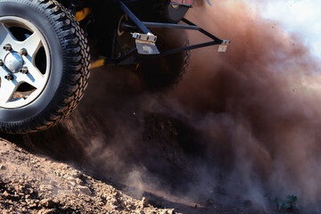 Dust and earth fly out from under the wheels of the buggy, close-up.