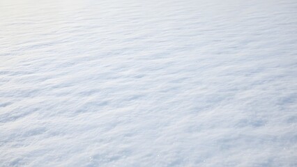 Closeup of fresh, textured snow surface in winter, showing soft ripples and bright white color under natural light