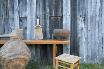 Objects of ancient village life near a wooden wall.
