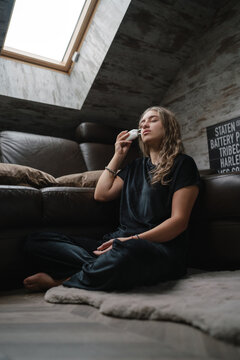 Relaxed Woman Seated Comfortably Under Natural Sunlight Performing Mindful Facial Procedures