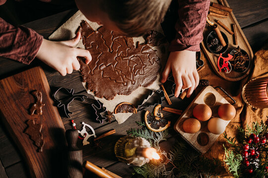 Child making gingerbread cookies with festive cutters