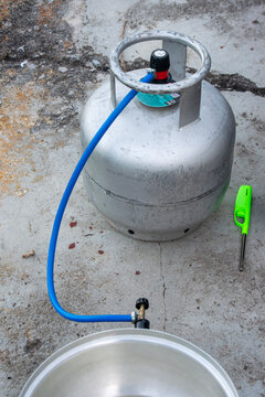 Propane tank with hose and lighter on concrete
