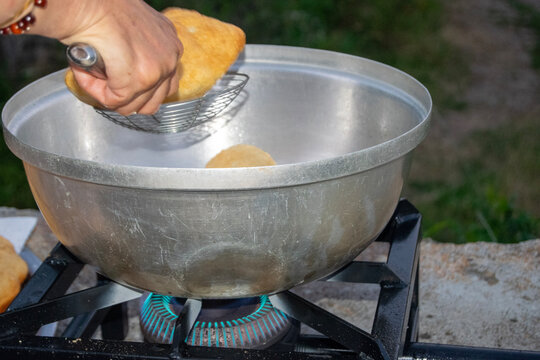 Cooking empanadas in a large frying pot outdoors