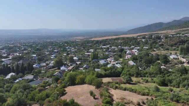 Panoramic aerial view of a picturesque rural village surrounded by green forests and mountains in Sheki, Azerbaijan