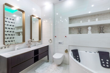 This space features a modern bathroom setup with a large bathtub, double sinks, two mirrors, and stylish storage areas. Bright lights enhance the overall look and feel
