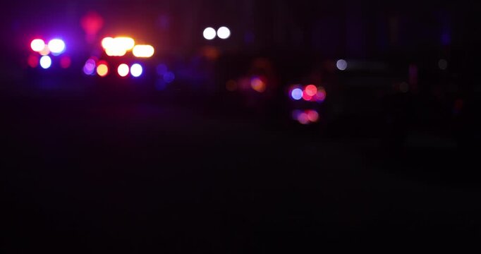 Abstracted illuminated night view of police units on a city street.