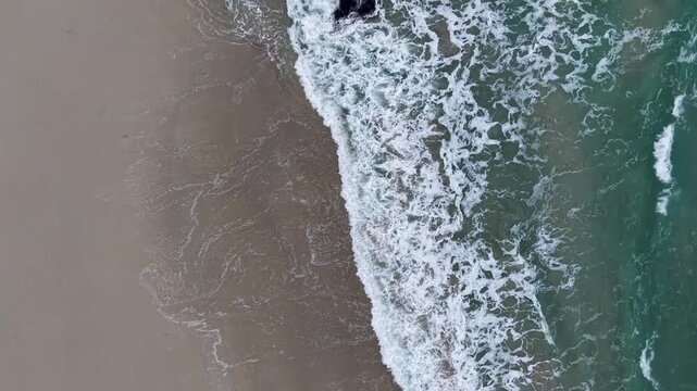Ocean waves breaking on a sandy beach below a cloudy sky in ferrol, galicia