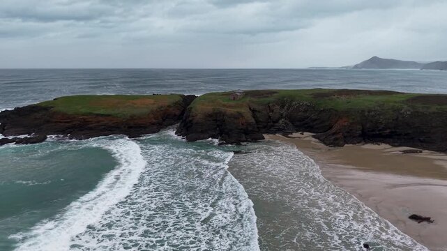 Ocean waves breaking on a sandy beach below a cloudy sky in ferrol, galicia