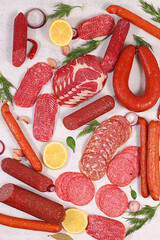Selection of various smoked and dry-cured sausages, sliced salami, and spices on a kitchen counter. Advertising and menu for a store, banner for a cafe or restaurant. Delicious holiday appetizers
