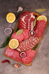 Delicious, aromatic appetizers of various salami cuts for the holidays. A selection of various smoked and dry-cured sausages and spices on a kitchen background. Advertising and menu for a store