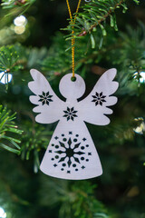 Wooden angel decoration hangs on a branch of a pine tree during winter holiday season