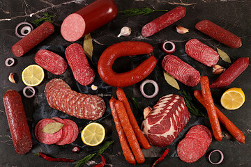 Delicious, aromatic appetizers of various salamis for the holidays. A selection of various smoked and dry-cured sausages and spices on a kitchen background. Advertising and menu for a store,
