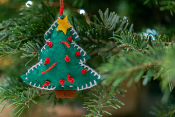 Handmade decoration hanging on green pine tree during holiday season in a cozy indoor setting