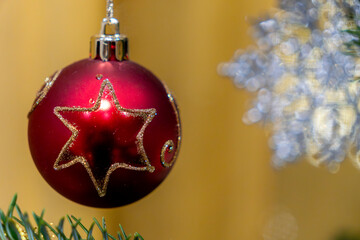 Red ornament hangs on a pine tree with a blurred background during Christmas season