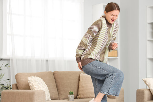 Young woman with hemorrhoids and cactus on sofa at home