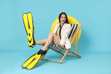 Businesswoman with flippers in deck chair on light blue background © New Africa