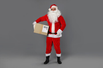 Santa Claus with parcel on grey background