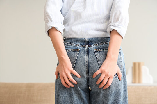 Young woman with hemorrhoids at home, back view