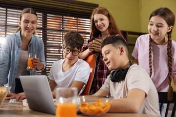 Teenagers playing online game on computer and having snacks at home