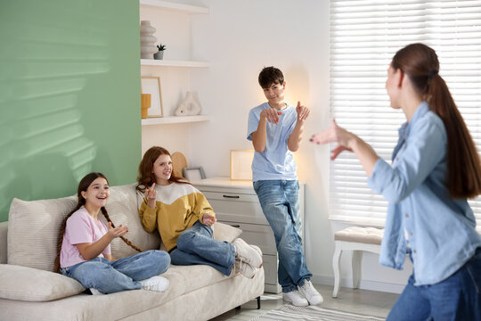 Group of teenagers playing charades game at home