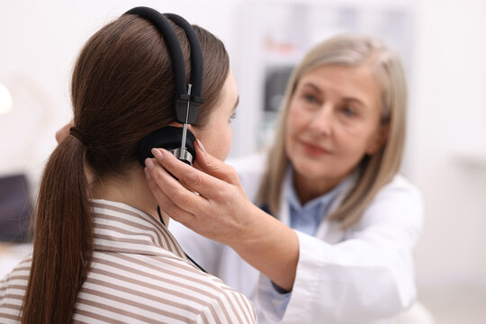 Hearing test. Doctor adjusting patient's audiometric headphones in clinic, selective focus