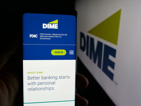 Stuttgart, Germany - 12-05-2025: Person holding cellphone with webpage of US financial company Dime Community Bank on screen in front of logo. Focus on center of phone display.