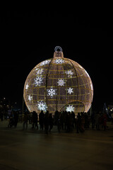 Giant illuminated christmas ornament with people celebrating holiday