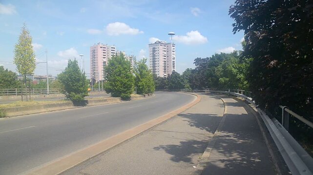 Quarto Oggiaro, Italy. Road with guardrail. Skyline of the city from street Palizzi with cars and a passing yellow tram. District of Milan from which it is a few km