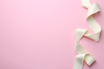 Beautiful beige ribbon on pink background, top view. Space for text