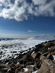Rocky mountain slope with snow under blue sky and clouds in winter.